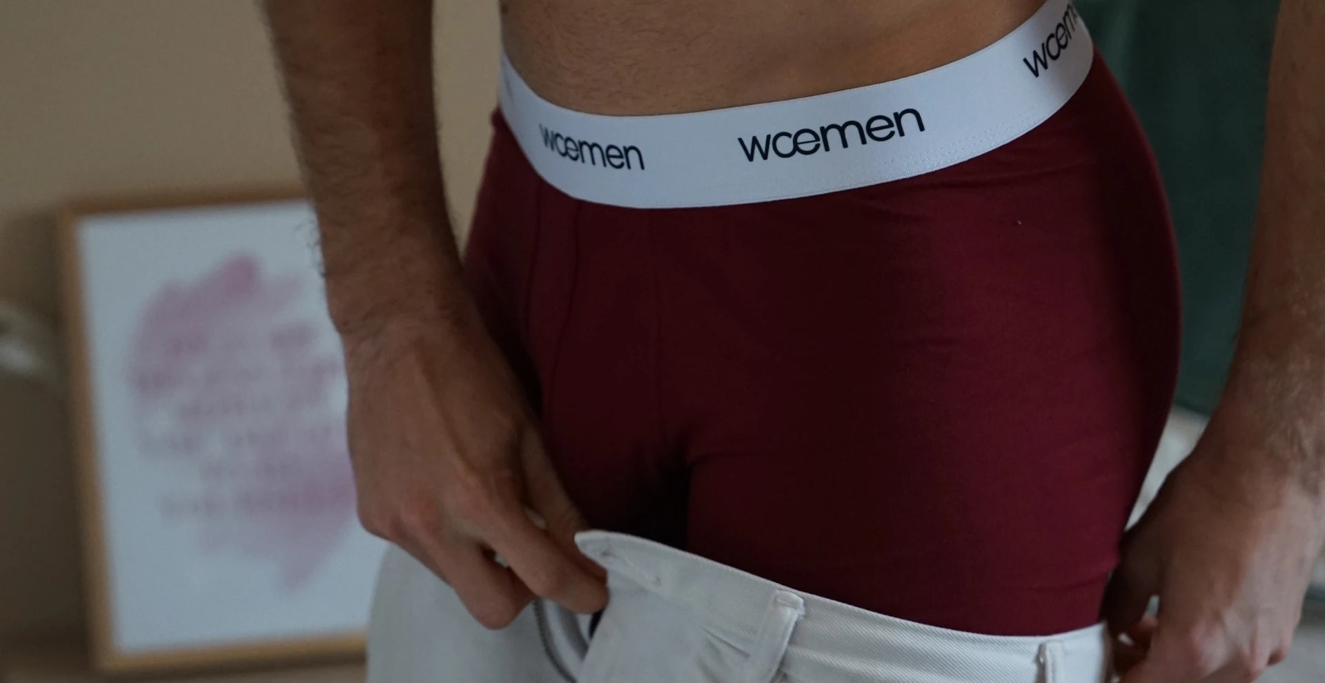 Homme en boxer rouge bordeaux de la marque woemen qui remet son pantalon.